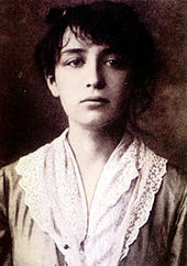 Head and shoulders of a young, dark haired woman looking downward.