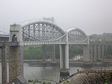 a bridge spanning a river at high level, the bridge deck supported in the centre by curved tubular metal girders
