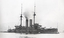 Large warship with smoke rising from the smokestack.