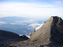 A view from Low's peak, with a smaller peak to the right of the photo, with forested mountains in the background